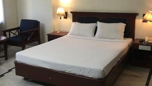A hotel room with a large bed, two bedside tables, a chair, and two wall lamps. - Fabhotel Prime The Vijay Park Arumbakkam (Chennai)
