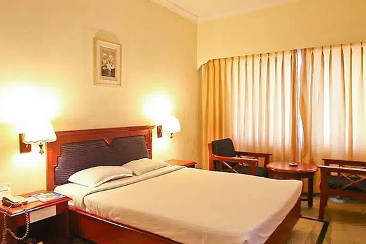 Ein Hotelzimmer mit Bett, Nachttischen, einem Schreibtisch und einem Sessel.