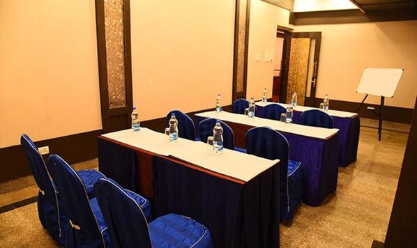 A conference room with long tables, blue chairs, and water bottles.