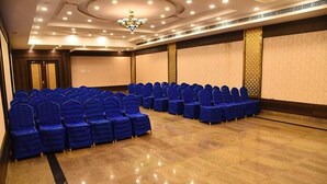 A conference room with rows of blue chairs, a chandelier, and a polished wooden floor. - Fabhotel Prime The Vijay Park Arumbakkam (Chennai)