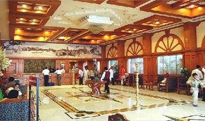 A spacious lobby with a high ceiling, ornate wood paneling, and a large mural.
