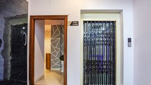 A hotel entrance with a wooden door, a metal gate, and a sign indicating the first floor. - Fabhotel Olive Stay Inn (Nagpur)