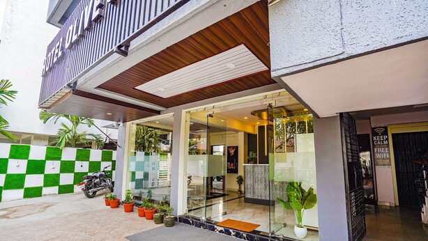 A hotel entrance with a checkered wall, potted plants, and a motorcycle parked outside. - Fabhotel Olive Stay Inn (Nagpur)