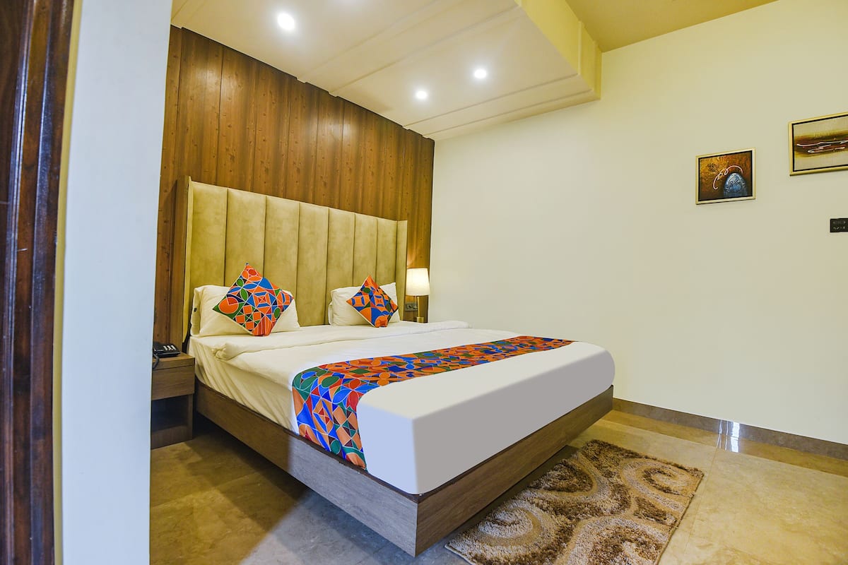 A hotel room with a large bed, wooden headboard, and a patterned rug.
