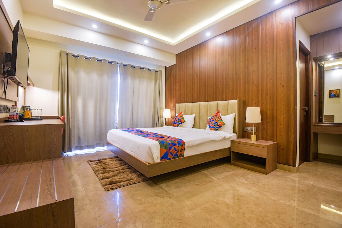 A hotel room with a large bed, bedside tables, a desk, and a television.