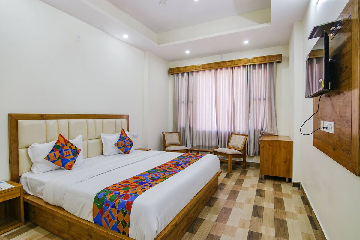 A hotel room with a large bed, a TV mounted on the wall, a desk, and a chair.