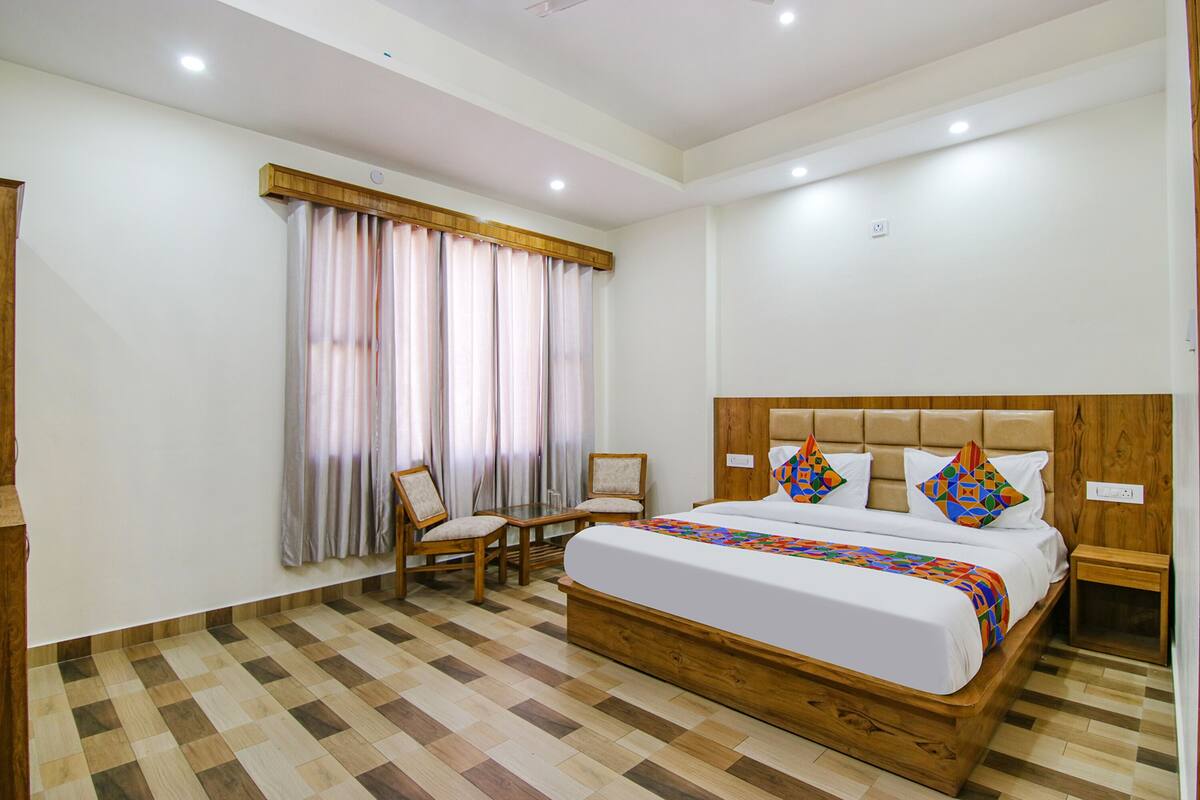 A bedroom with a large bed, two chairs, a small table, and a nightstand.