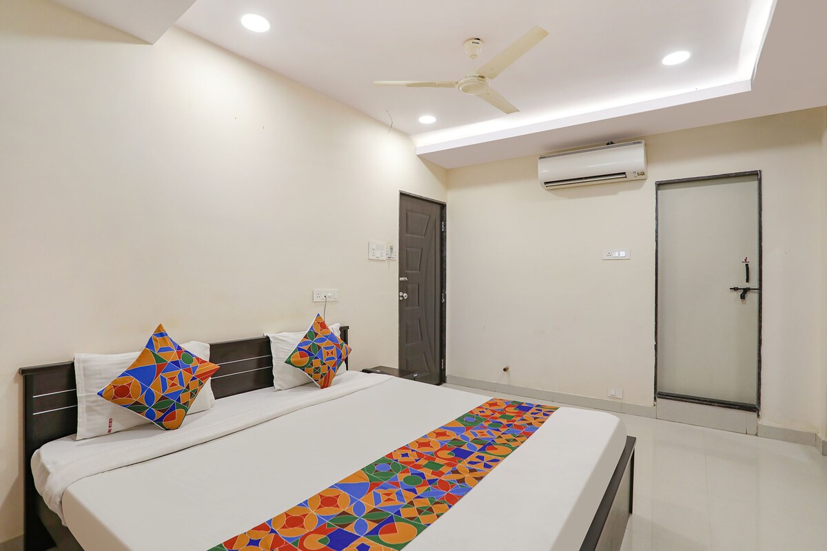 A hotel room with a bed, a ceiling fan, an air conditioning unit, and a door.