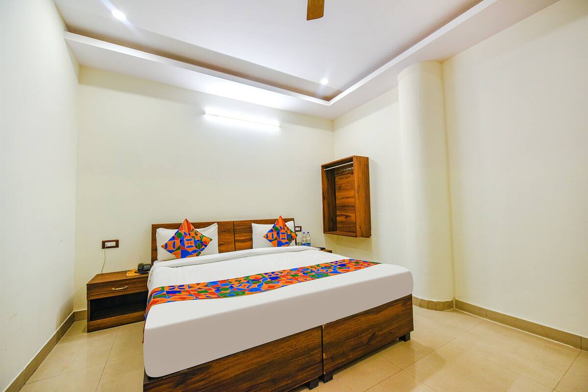 A bedroom with a wooden bed, white bedding, and a nightstand.