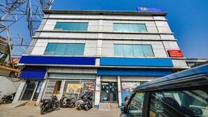 A multi-story hotel with a blue awning, a sign for FabHotels, and a visible entrance with a motorcycle parked outside. - Fabexpress Alaknanda Paradise (Dehradun)