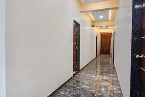 Un pasillo con suelo de mármol, paredes blancas y puertas de madera.