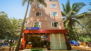 A tall brick building with a sign for Fab Hotels, featuring a modern entrance and surrounding palm trees. - Fabhotel Tree Suites (Bengaluru)