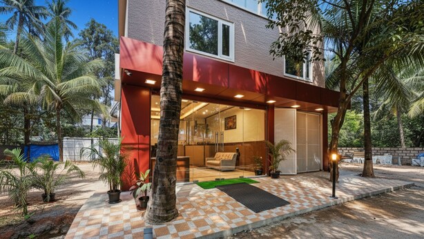 A modern house with a covered patio, a large window, and a door leading to an interior space. - Fabhotel Tree Suites (Bengaluru)