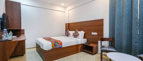 Habitación de hotel con cama de madera, un escritorio con silla, una mesita y un ventilador de techo.