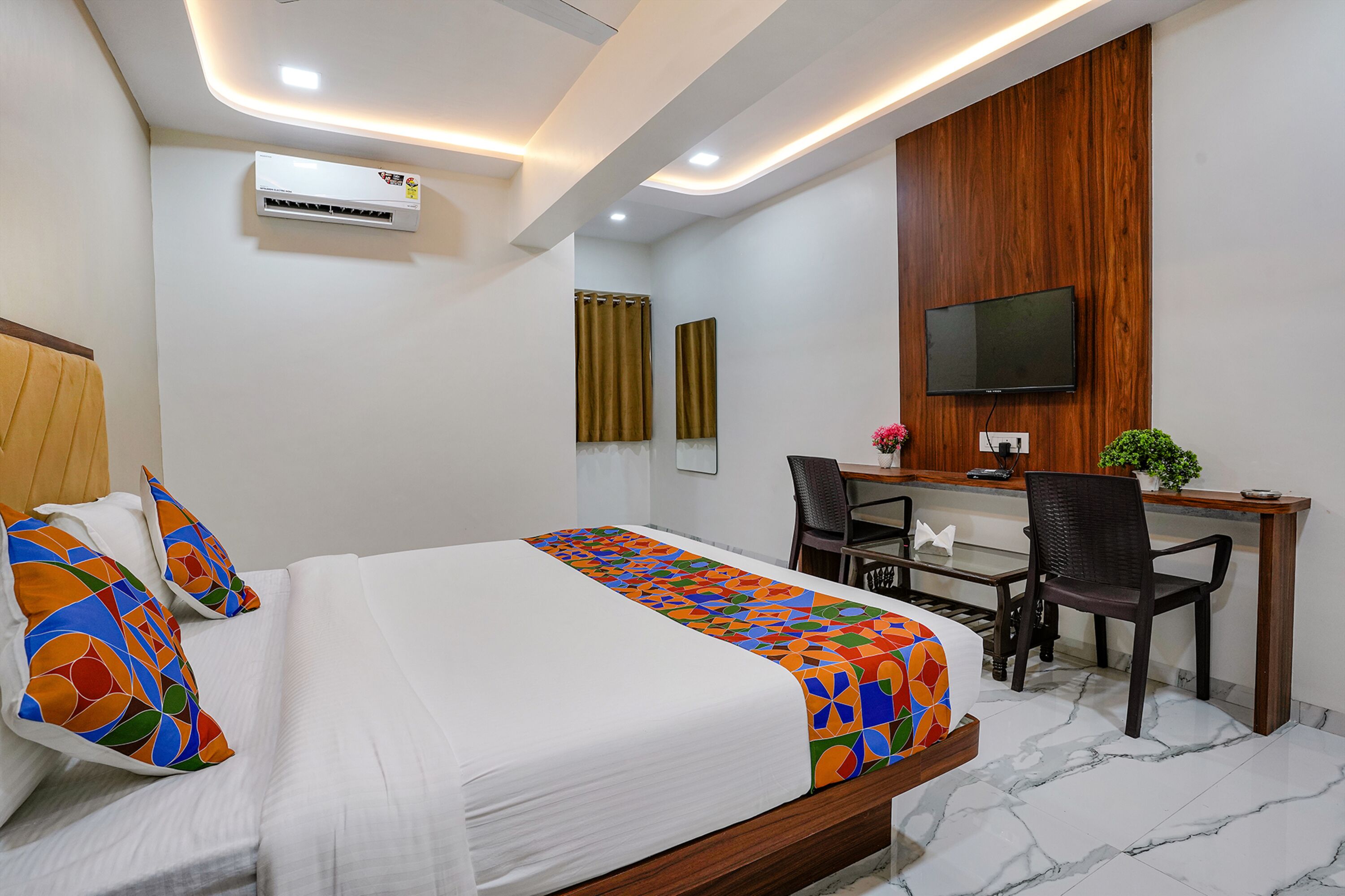 Une chambre d’hôtel équipée d’un lit, d’un bureau, d’une chaise, d’une télévision et d’un appareil de climatisation.