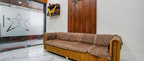 A reception area with a wooden sofa, a star-shaped glass wall, and a mounted television.