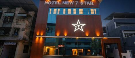 A modern hotel building with a prominent star logo and the name "Hotel New 7 Star" displayed above the entrance.