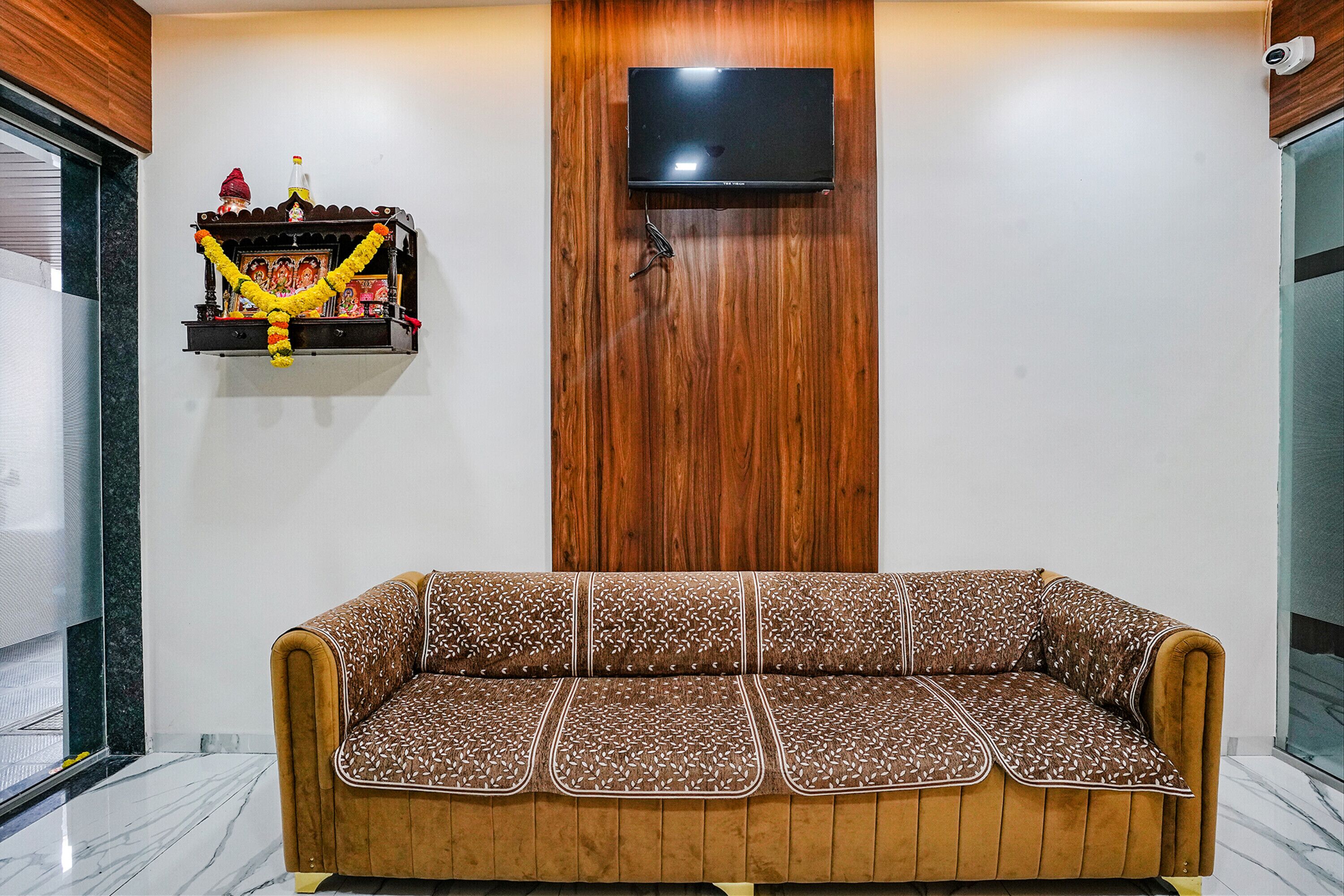 A modern living room with a wooden wall panel, a mounted TV, and a decorative shelf with religious items.