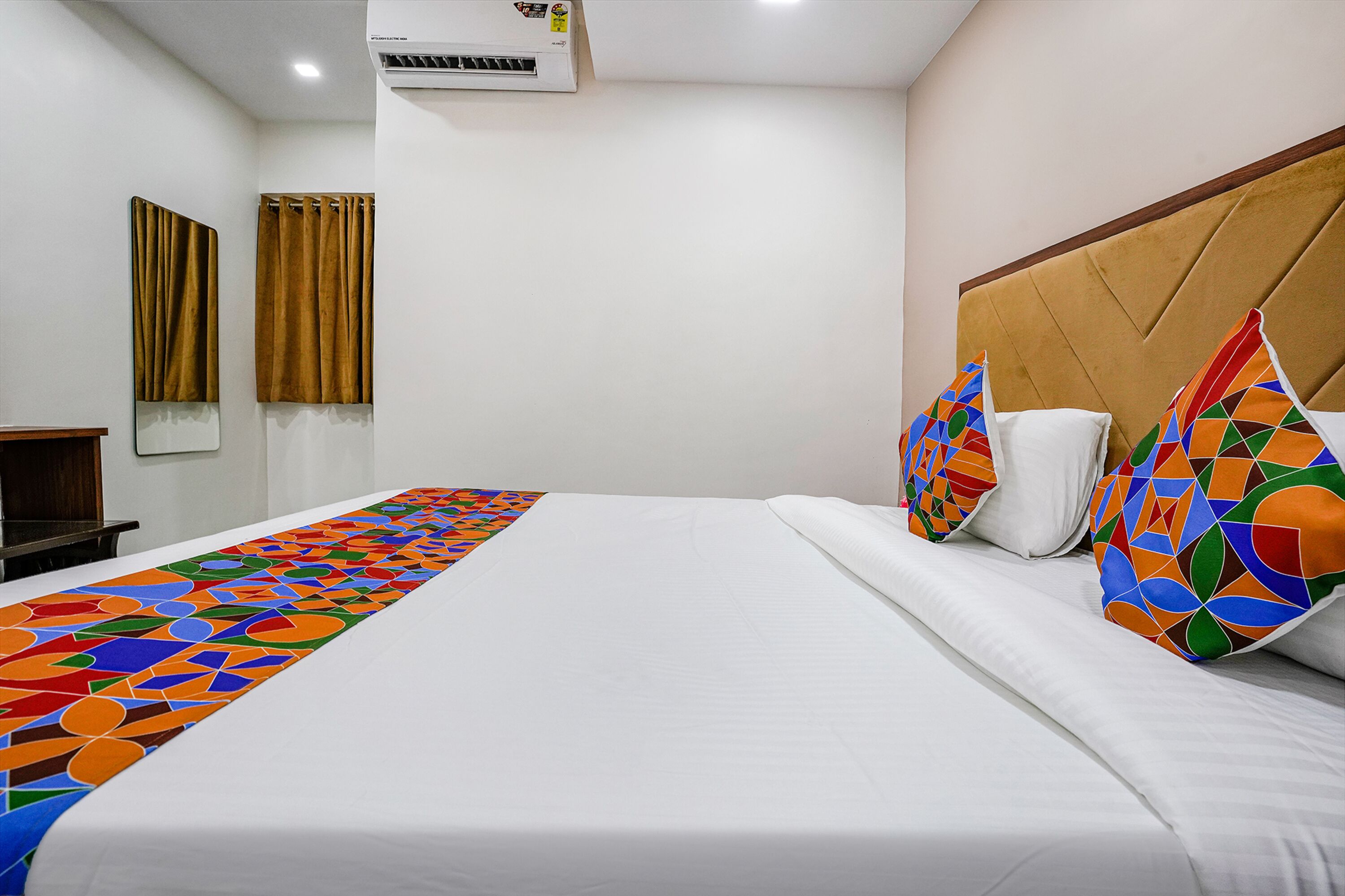 Une chambre d’hôtel avec un grand lit, une tête de lit, une fenêtre avec des rideaux et un appareil de climatisation.