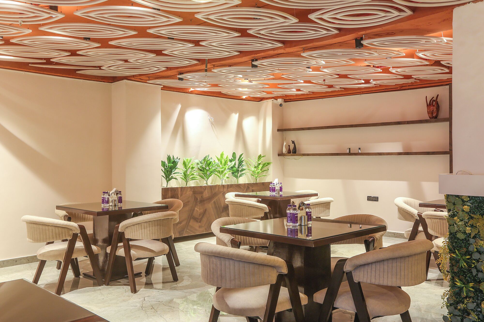 A modern dining area with a unique ceiling design, a central plant display, and a clean, minimalist decor.