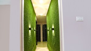 A hallway with green artificial grass walls and a light-colored floor. - Fabhotel The Sunshine Residency (Barasat)