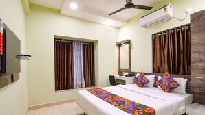A hotel room with a bed, a desk, a chair, a TV, and an air conditioning unit. - Fabhotel The Sunshine Residency (Barasat)