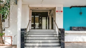 A staircase leading to a hotel lobby with a blue wall and a sign indicating car parking at owner's risk. - Fabexpress Shanti Inn (Nashik)