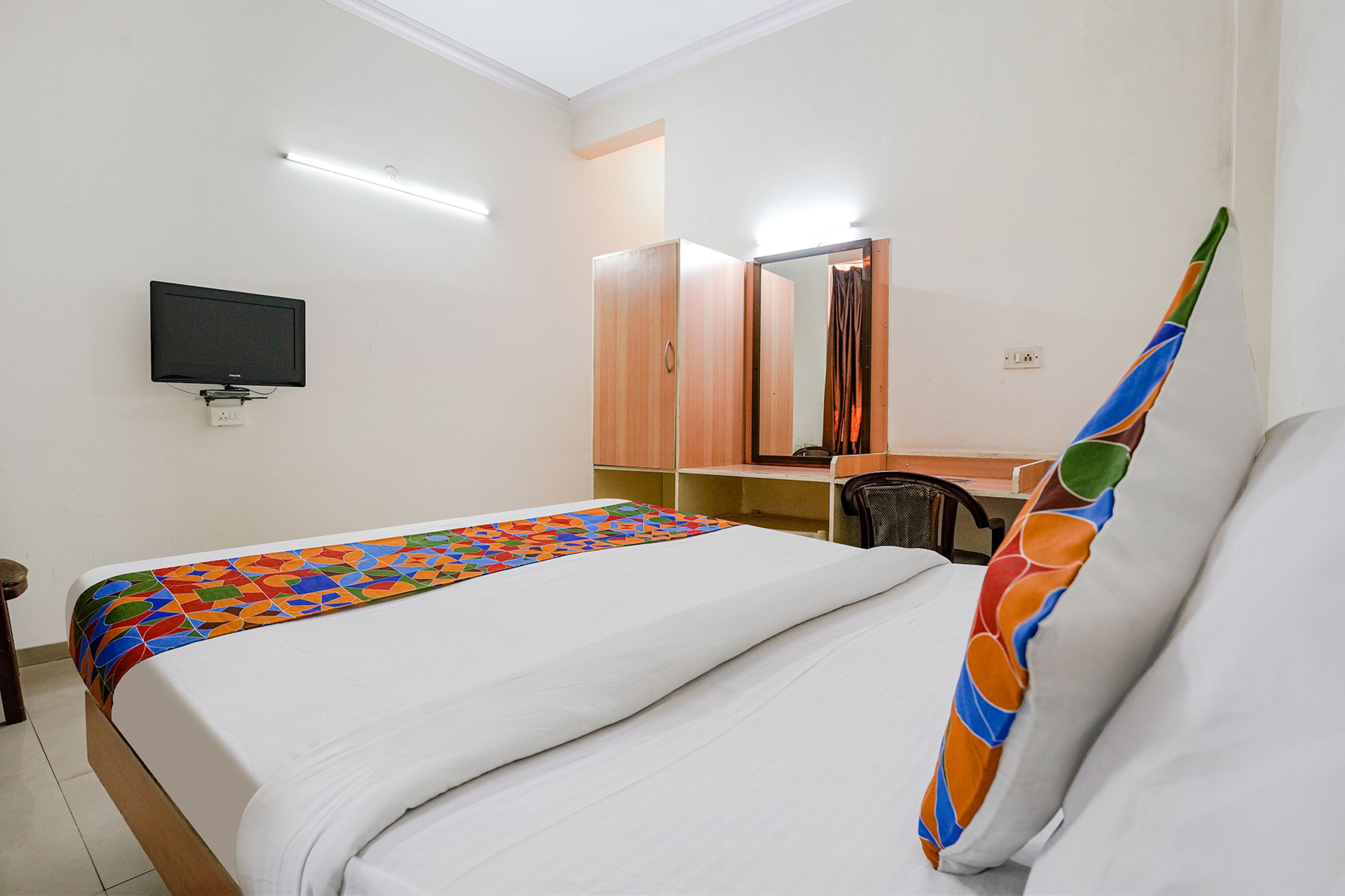 Une chambre d’hôtel équipée d’un lit, d’un téléviseur fixé au mur, d’un bureau et d’une chaise.