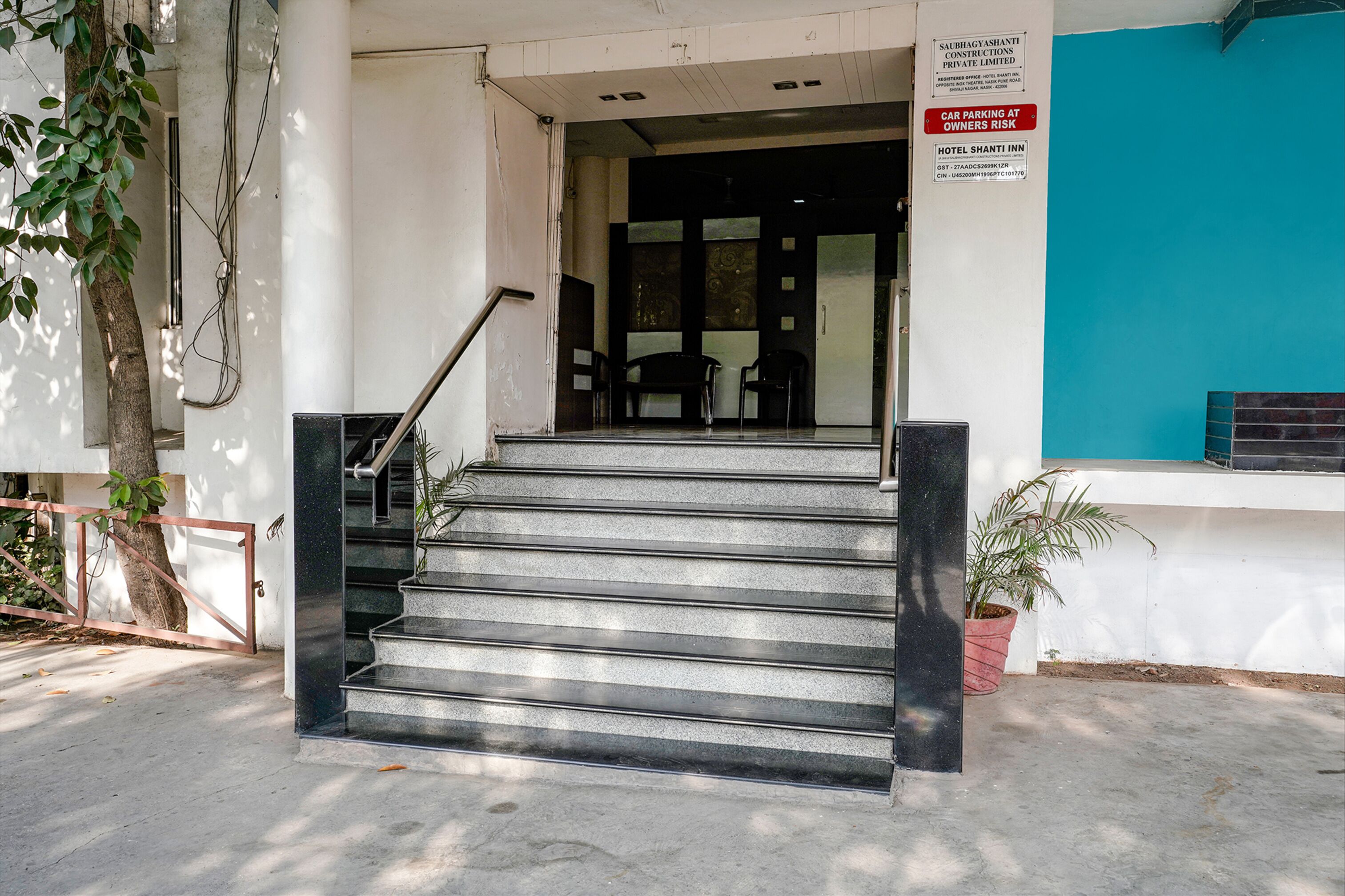 Una escalera conduce a la entrada de un hotel, con un letrero que indica que el estacionamiento se realiza bajo la responsabilidad del propietario.