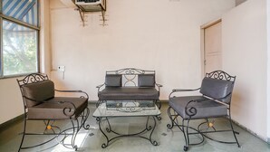 A room with a glass-top table, two cushioned chairs, and a wall-mounted air conditioner. - Fabexpress Shanti Inn (Nashik)