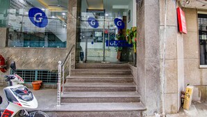 A hotel entrance with a marble staircase, a scooter parked outside, and a sign with a blue 'G' logo. - Fabhotel The Glory I (New Delhi)