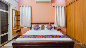 Un dormitorio con cama, dos almohadas, cabecero, armario de madera y ventilador de techo.
