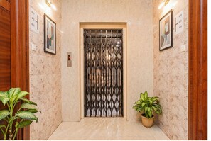 An elevator with a metal gate, marble walls, and potted plants. - Fabhotel Q Suites (Hyderabad)