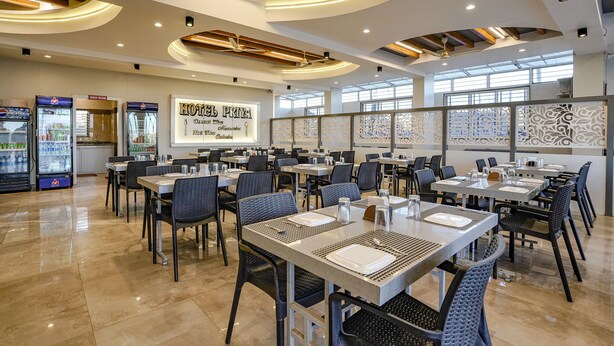 Un restaurant modern amb un sostre alt, il·luminació empotrada i una paret central amb la carta de plats.