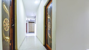 A hallway with two doors, each with a decorative design, leading to a room with a bed and a window. - Via Tasty Buds - 300m From Calangute Beach (Baga)