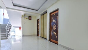 A hallway with a staircase, a fire alarm, and a door with a decorative design. - Via Tasty Buds - 300m From Calangute Beach (Baga)