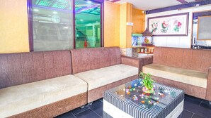 A modern living room with a brown sofa, a glass coffee table with colorful decorations, and a fish tank. - Fabhotel Golden Horizon (Ranchi)