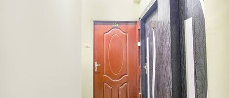 A hallway with a wooden door labeled 304, a black door with a tree branch design, and a white door with a similar design.
