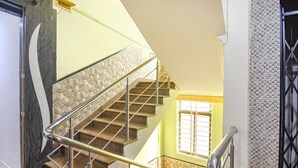 A staircase with stone steps and metal railings, leading to a landing with a window. - Fabhotel Golden Horizon (Ranchi)