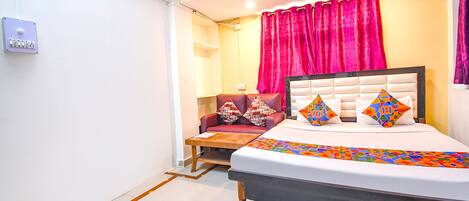 A bedroom with a bed, a nightstand, a chair, and a window with curtains.