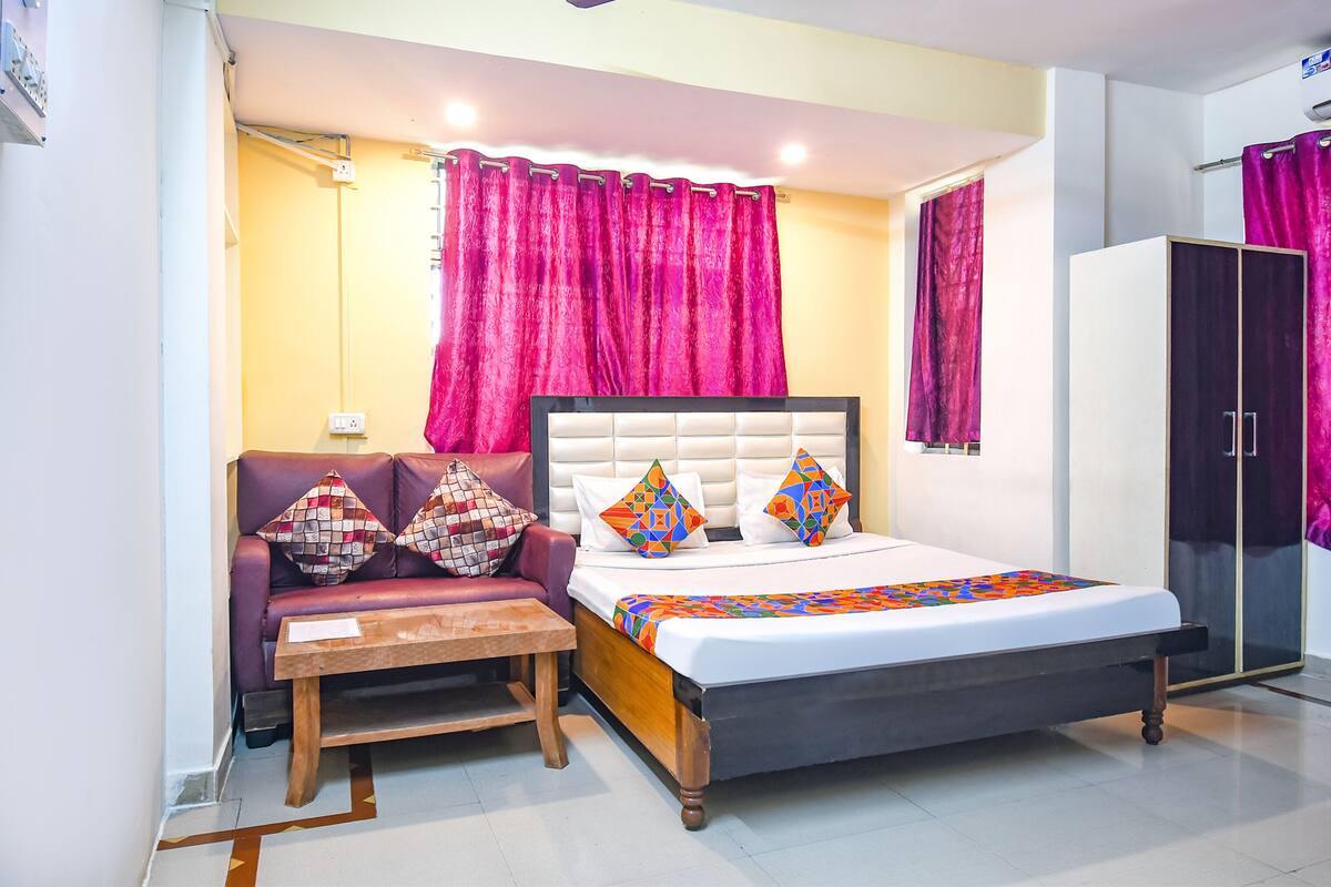 A bedroom with a bed, a sofa, a table, and a wardrobe.