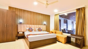 A modern hotel room with a large bed, wooden wardrobe, and a view of the outdoor seating area. - FabHotel Morjim Bliss - Nr. Morjim & Ashwem Beach (Morjim)