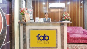 A hotel reception desk with a 'fab hotels' sign, a reception area, a red sofa, and an air conditioning unit. - FabHotel Morjim Bliss - Nr. Morjim & Ashwem Beach (Morjim)