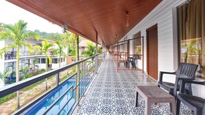 A balcony with a pool, chairs, and a view of other buildings and palm trees. - FabHotel Morjim Bliss - Nr. Morjim & Ashwem Beach (Morjim)