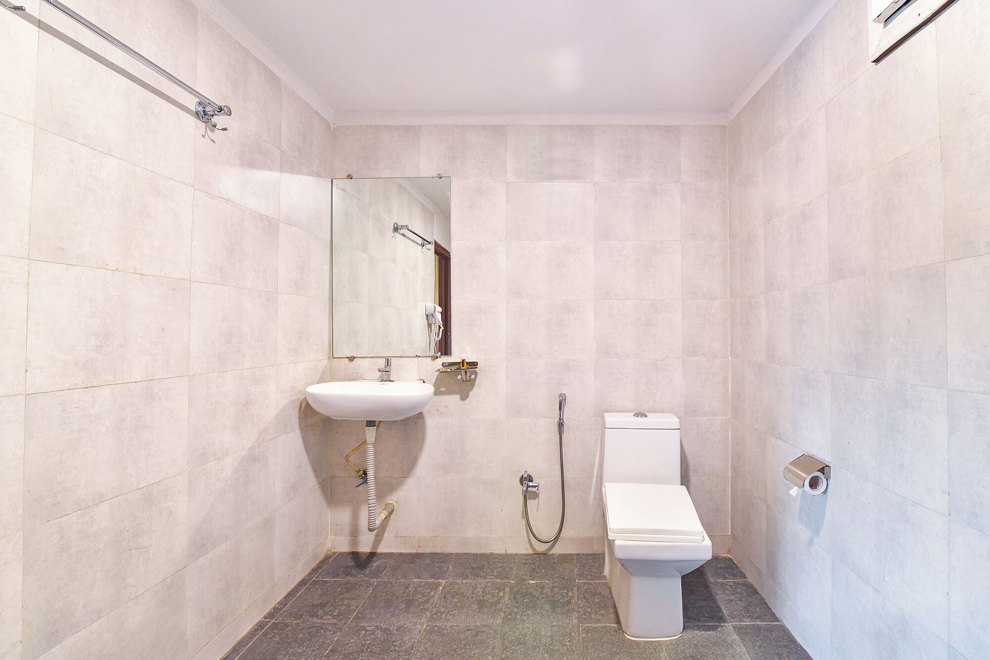 A small, modern bathroom with a white sink, mirror, and toilet.