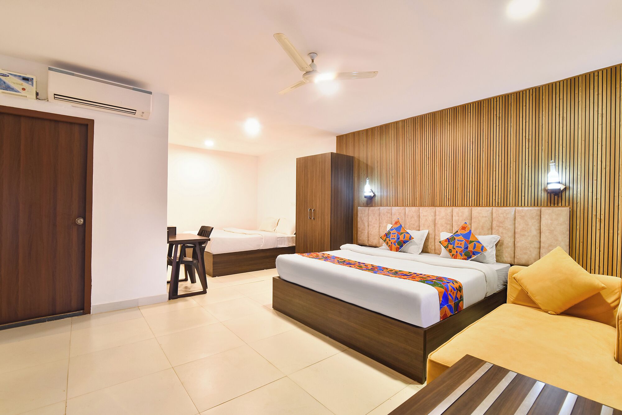 A hotel room with a bed, a desk, a wardrobe, and a ceiling fan.
