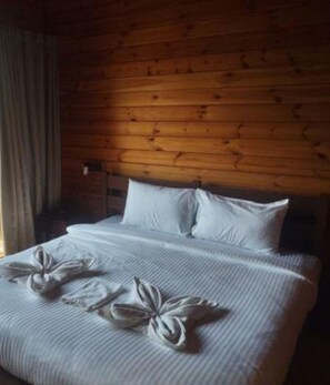 A neatly made bed with white linens and pillows, a wooden headboard, and a window with curtains. - Fabhotel Levels By The Sea (Vagator)