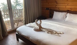 A hotel room with a bed, wooden headboard, and a view of palm trees through a glass door. - Fabhotel Levels By The Sea (Vagator)