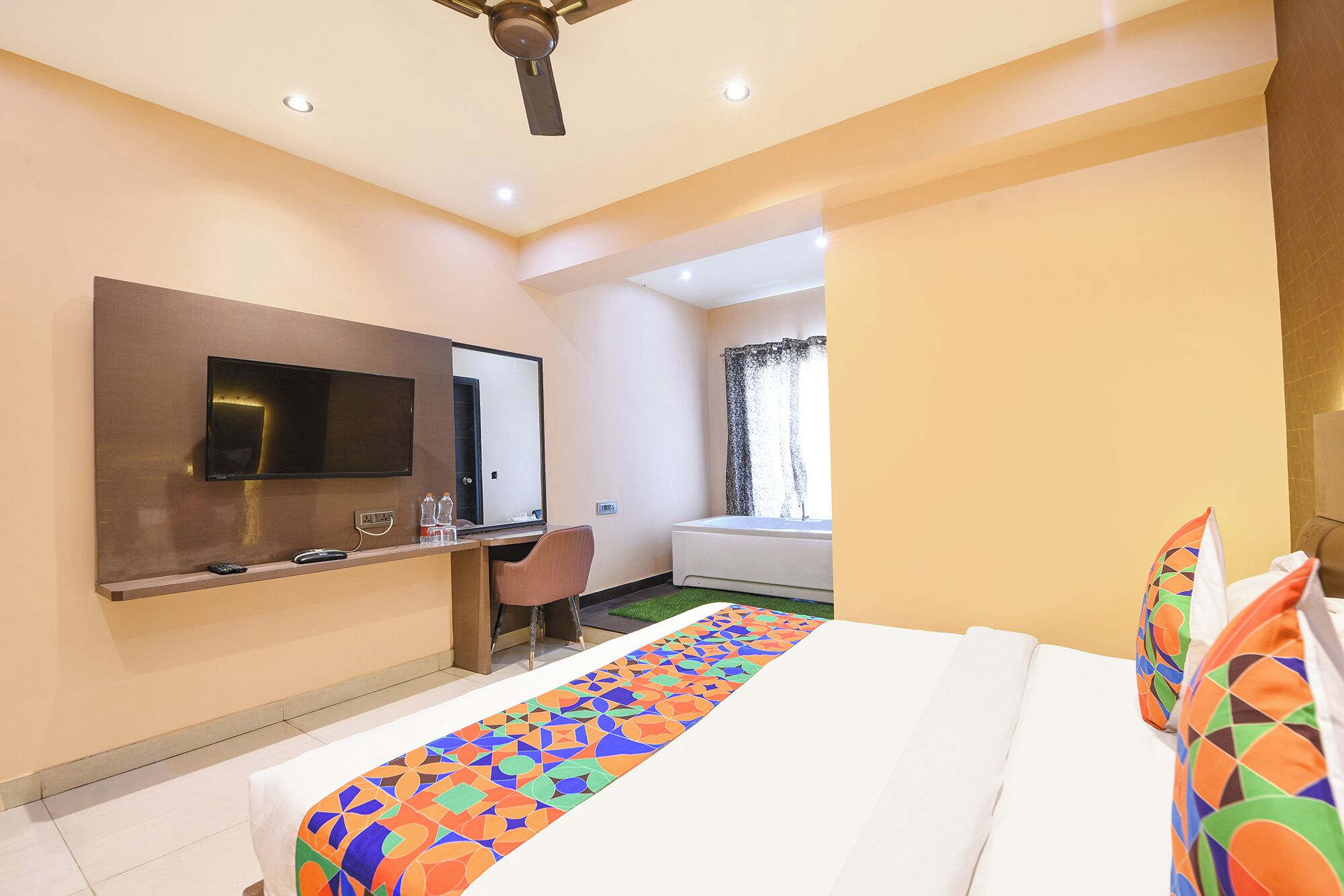 A hotel room with a bed, a desk, a television, and a window.