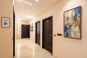A hotel corridor with dark wooden doors, a checkered floor, and a large abstract painting on the wall. - Fabhotel 19 West (New Delhi)